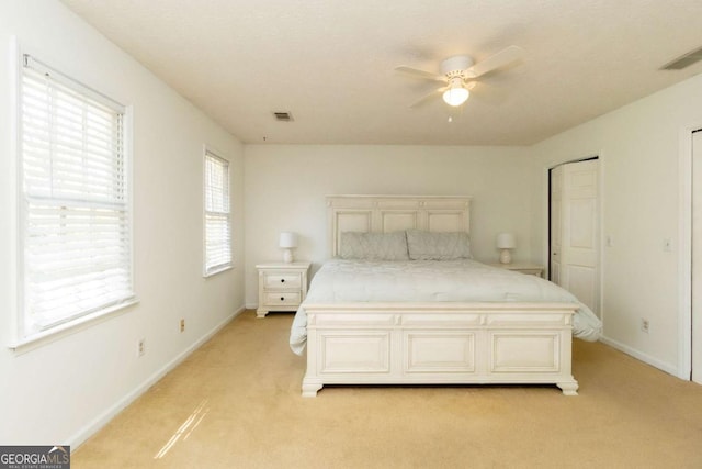 bedroom featuring baseboards, ceiling fan, visible vents, and light colored carpet