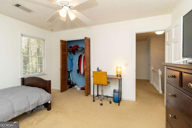 bedroom featuring baseboards, a textured ceiling, visible vents, and light carpet