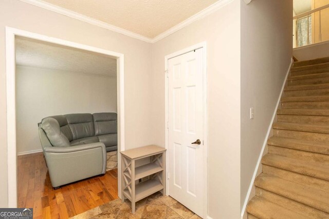 sitting room featuring stairs, wood finished floors, a textured ceiling, baseboards, and ornamental molding