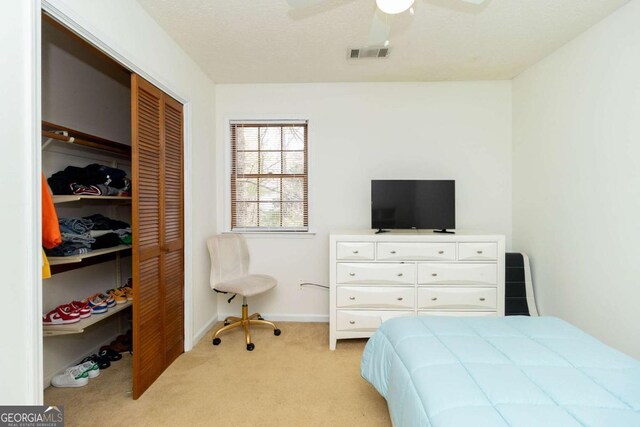 bedroom with a closet, baseboards, light colored carpet, visible vents, and ceiling fan