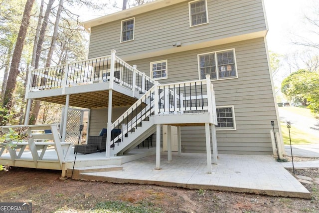 rear view of house featuring a wooden deck, stairway, and a patio area