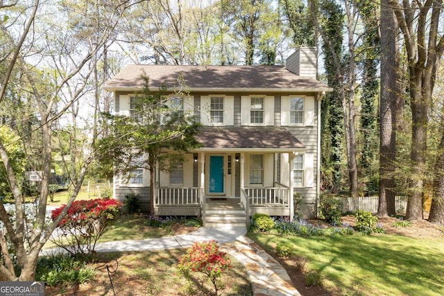 colonial inspired home featuring a front lawn, a chimney, covered porch, and fence