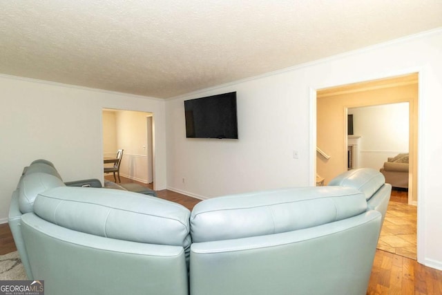 living area with ornamental molding, a textured ceiling, baseboards, and wood finished floors