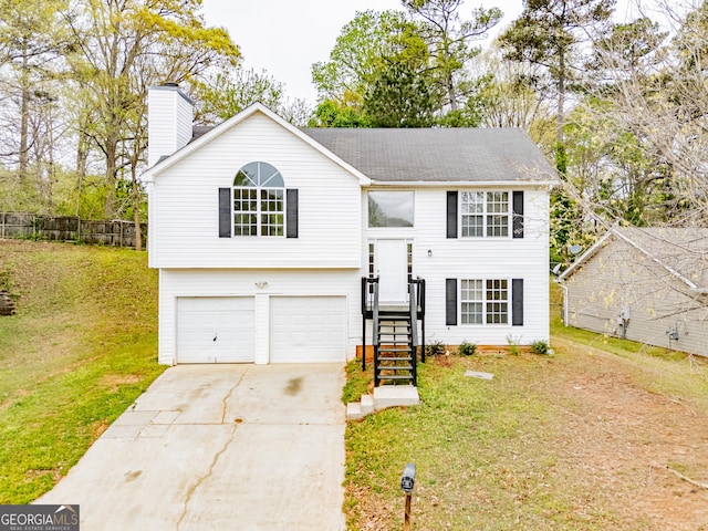 split foyer home with fence, an attached garage, a chimney, a front lawn, and driveway