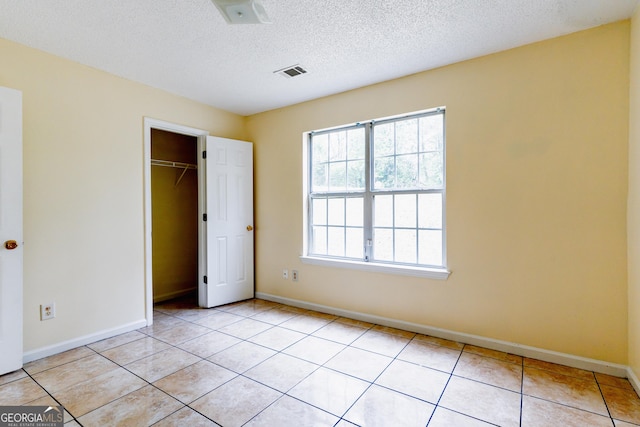 unfurnished bedroom featuring light tile patterned floors, baseboards, a textured ceiling, visible vents, and a closet