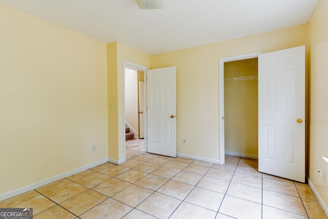 unfurnished bedroom with light tile patterned flooring, baseboards, and a closet