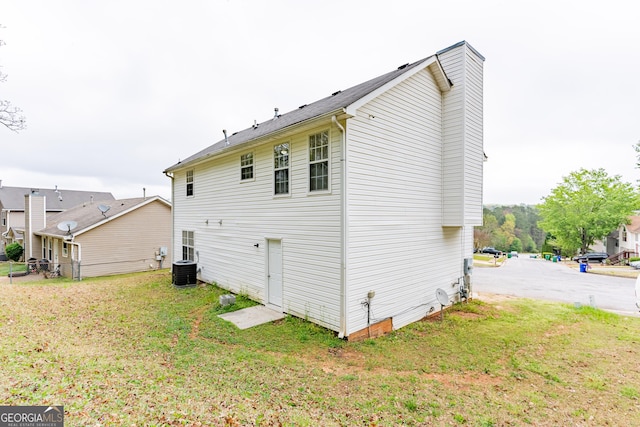 view of side of home featuring a chimney and a yard