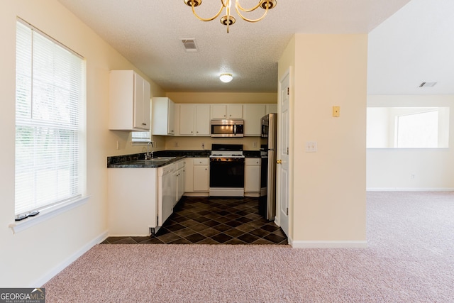 kitchen featuring dark countertops, stainless steel appliances, dark carpet, and visible vents