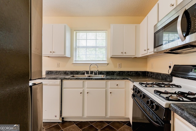 kitchen featuring dishwasher, stainless steel microwave, range with gas cooktop, dark countertops, and a sink