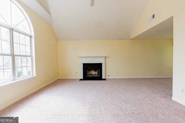 unfurnished living room with carpet flooring, a fireplace with flush hearth, lofted ceiling, baseboards, and visible vents