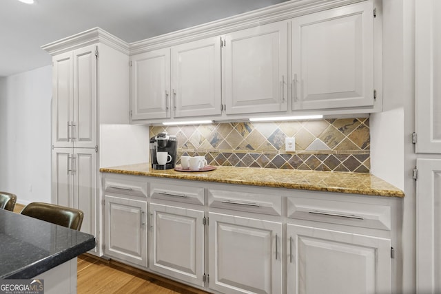 kitchen featuring light stone countertops, decorative backsplash, and white cabinets
