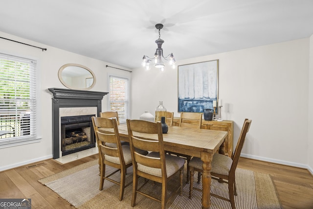 dining space featuring hardwood / wood-style floors, an inviting chandelier, a fireplace, and baseboards