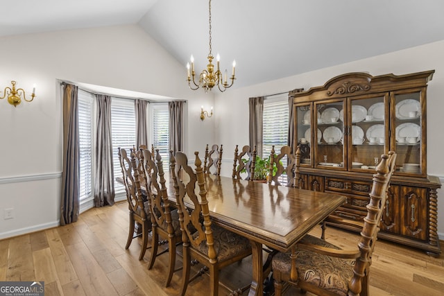 dining space with high vaulted ceiling, light wood-style floors, baseboards, and an inviting chandelier