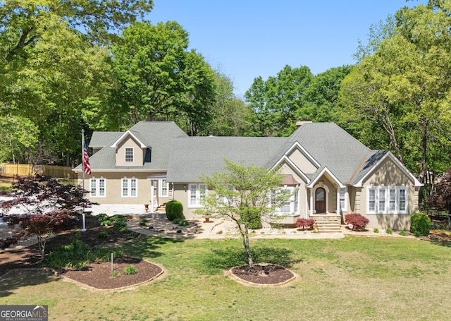 view of front facade featuring a shingled roof, a front yard, and fence