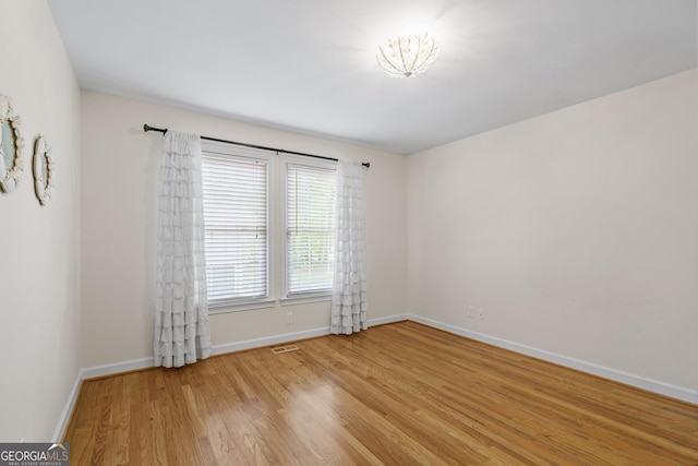 empty room featuring light wood-style flooring, baseboards, and visible vents