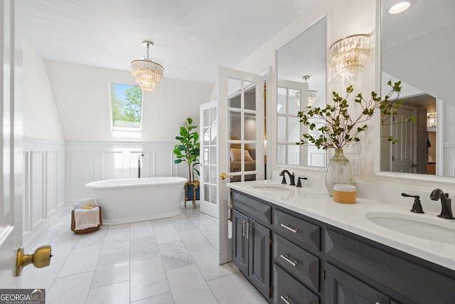 bathroom with an inviting chandelier, a freestanding tub, double vanity, and a sink