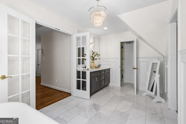 interior space featuring vanity, recessed lighting, marble finish floor, wainscoting, and a notable chandelier