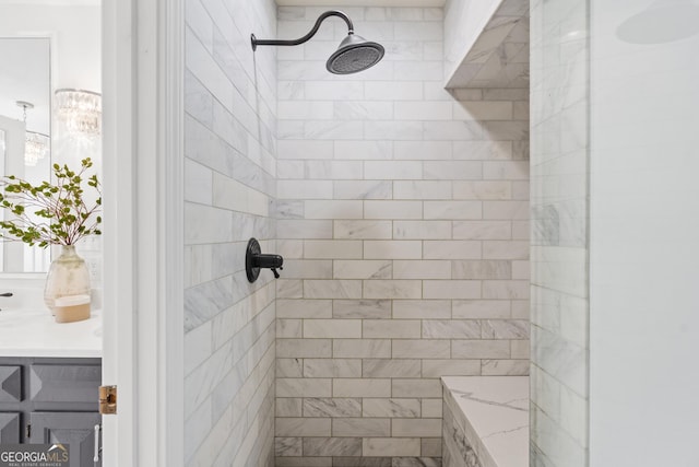 bathroom with a chandelier, tiled shower, and vanity