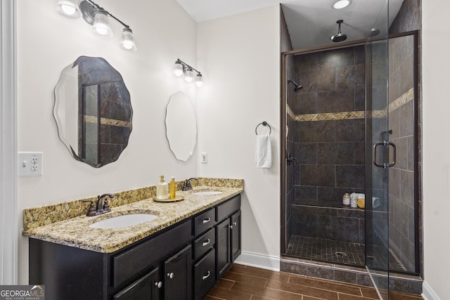 bathroom featuring a shower stall, baseboards, a sink, and wood tiled floor
