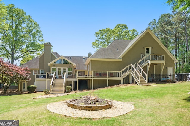 rear view of house with stairway, a fire pit, a deck, and a lawn