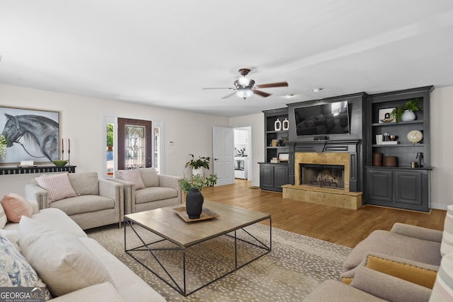 living room featuring a tiled fireplace, wood finished floors, and ceiling fan