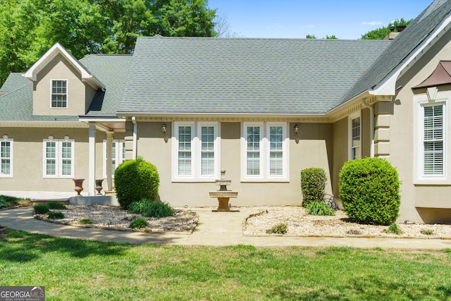 view of front facade featuring roof with shingles and stucco siding