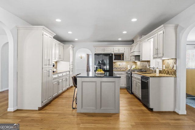 kitchen with tasteful backsplash, a center island, arched walkways, a sink, and stainless steel appliances