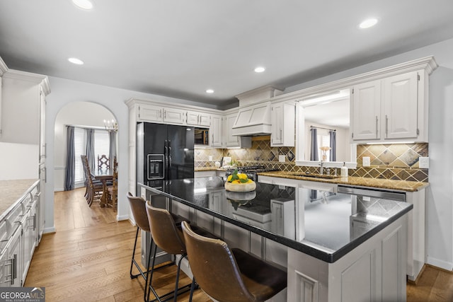 kitchen with custom exhaust hood, a center island, a sink, a breakfast bar area, and backsplash