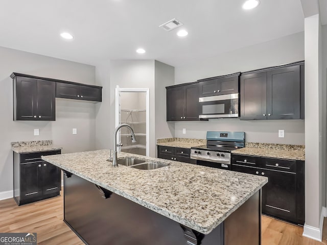 105 Hunts Mill Cir, Griffin, GA 30224 - kitchen with stainless steel appliances, light wood-type flooring, light stone counters, a center island with sink, and recessed lighting