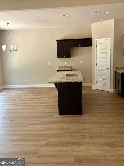 105 Hunts Mill Cir, Griffin, GA 30224 - kitchen with a chandelier, a center island, light wood-style floors, light stone counters, and recessed lighting