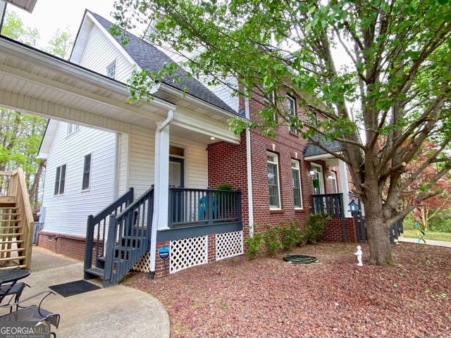 2210 Holly Springs Rd, Rockmart, GA 30153 - view of home's exterior with stairway, covered porch, a shingled roof, and brick siding