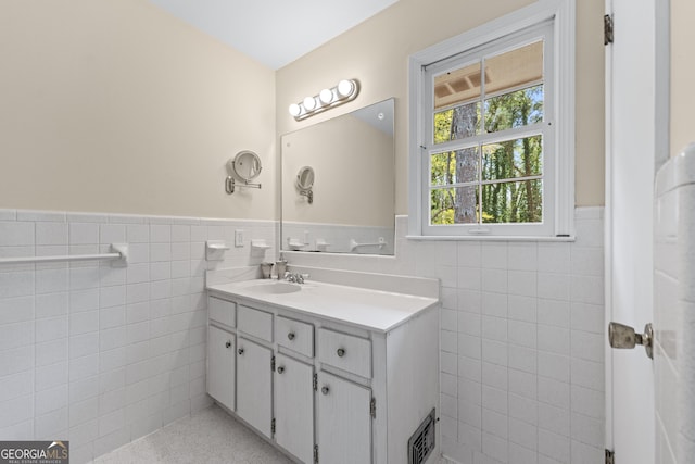 bathroom with vanity, tile walls, visible vents, and a wainscoted wall
