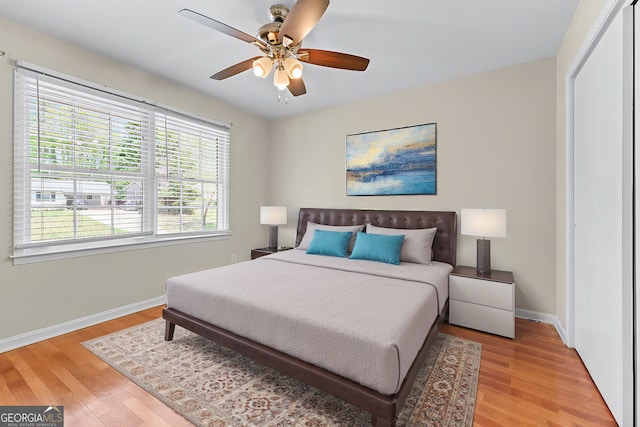 bedroom featuring light wood finished floors, baseboards, and ceiling fan