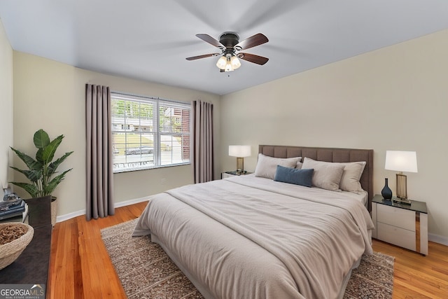 bedroom with light wood-type flooring, baseboards, and a ceiling fan