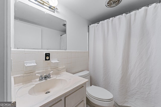 full bathroom featuring vanity, visible vents, toilet, wainscoting, and tile walls