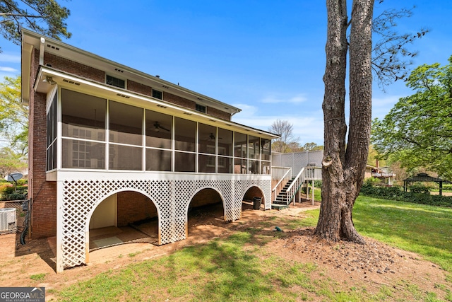 back of house with central AC, a sunroom, a yard, fence, and brick siding