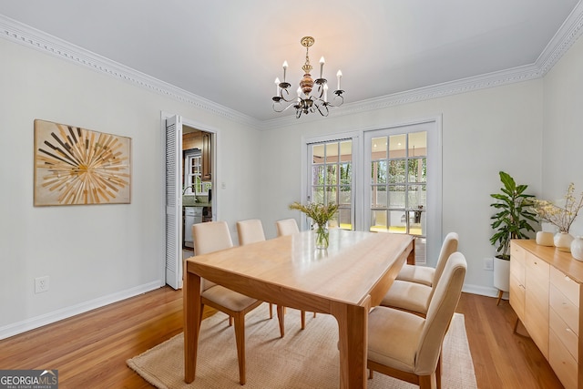 dining space featuring light wood-style flooring, baseboards, an inviting chandelier, and ornamental molding