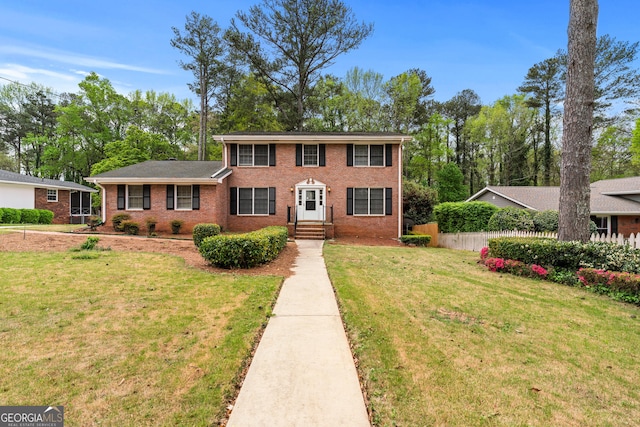 view of front of property with a front yard, fence, and brick siding