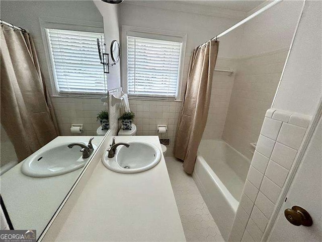 full bath featuring tile walls, vanity, ornamental molding, and shower / bathtub combination with curtain