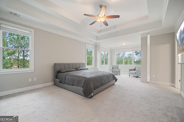 carpeted bedroom featuring a tray ceiling, baseboards, visible vents, and crown molding