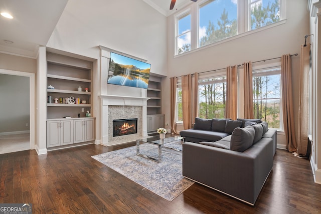 living area with baseboards, dark wood-style flooring, a ceiling fan, and a premium fireplace