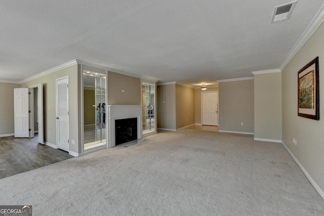 unfurnished living room with baseboards, visible vents, crown molding, and carpet flooring