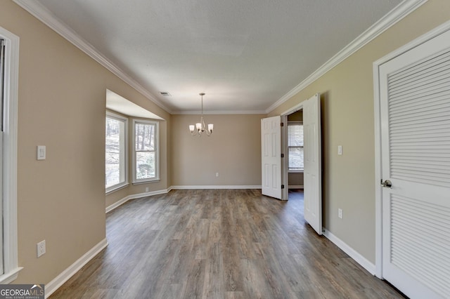 unfurnished dining area featuring ornamental molding, baseboards, a chandelier, and wood finished floors