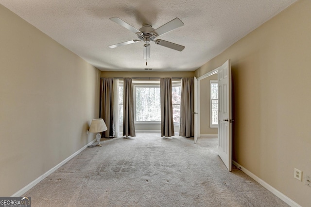 carpeted spare room with a textured ceiling, baseboards, and ceiling fan