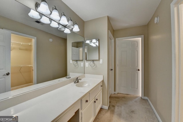 bathroom with a spacious closet, vanity, baseboards, and visible vents