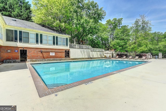community pool with fence and a patio area