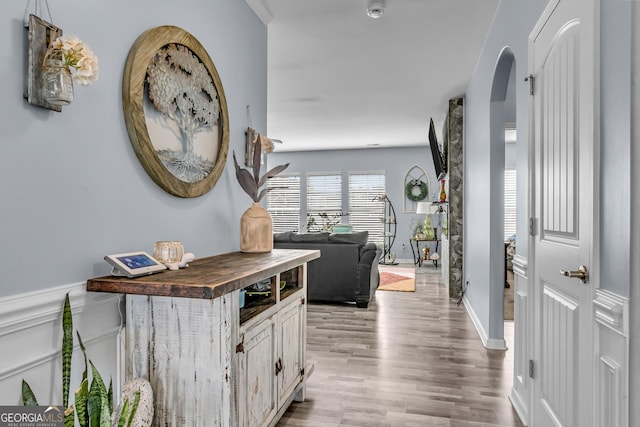 hallway with baseboards, wood finished floors, and arched walkways
