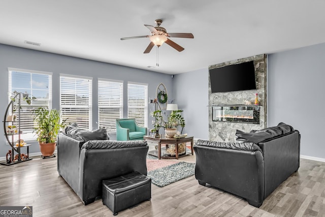 living area featuring a ceiling fan, visible vents, light wood-style flooring, and a fireplace