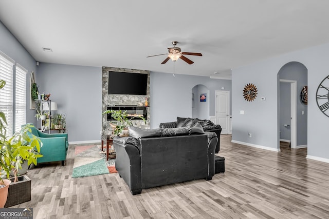 living room featuring wood finished floors, a ceiling fan, and arched walkways