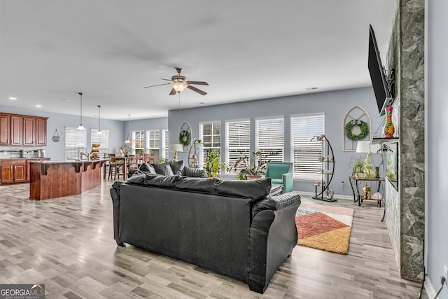 living room featuring ceiling fan, recessed lighting, light wood finished floors, and baseboards